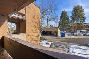 View of snowy exterior featuring brick siding, a residential view, and a balcony