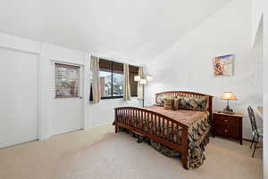 Carpeted bedroom featuring brick wall and lofted ceiling