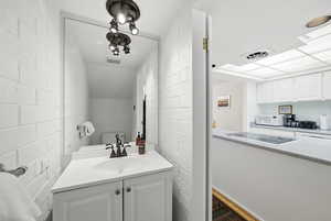 Half bathroom featuring vanity, concrete block wall, and brick wall