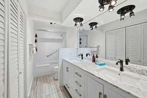 Full bathroom featuring a closet, double vanity, shower / bath combination with glass door, and a chandelier