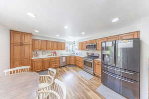 Kitchen with stainless steel appliances, light countertops, light wood finished floors, recessed lighting, and wood finish cabinetry
