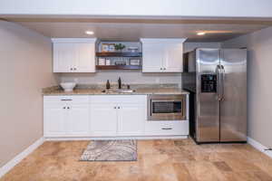 Kitchen featuring appliances with stainless steel finishes, white cabinetry, open shelves, recessed lighting, and light stone countertops