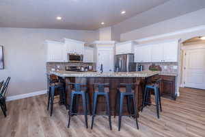 Kitchen featuring vaulted ceiling, white cabinetry, a kitchen breakfast bar, arched walkways, and tasteful backsplash