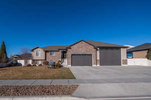 View of front of home featuring a gate, concrete driveway, an attached garage, and brick siding