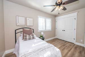 Bedroom featuring light wood finished floors, a closet, and a ceiling fan