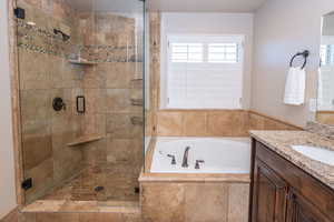 Full bathroom featuring a bath, vanity, and a stall shower