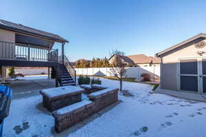 Snowy yard with a patio, a shed, a fenced backyard, and stairway