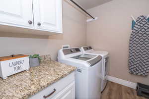 Washroom with dark wood-style flooring, washer and clothes dryer, and cabinet space