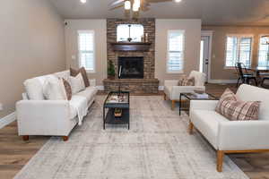 Living area featuring wood finished floors, ceiling fan, a stone fireplace, and recessed lighting