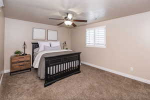 Bedroom with carpet floors, ceiling fan, and a textured ceiling