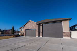 View of front of property with brick siding, driveway, a garage, and a shingled roof