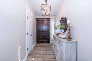 Entryway featuring a chandelier, light wood-type flooring, and lofted ceiling