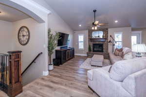 Living room with light wood-style floors, vaulted ceiling, a ceiling fan, arched walkways, and recessed lighting