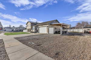 View of side of property featuring a residential view, driveway, an attached garage, brick siding, and a patio area