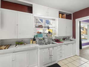 Kitchen featuring white cabinets, tile countertops, plenty of natural light, and light carpet