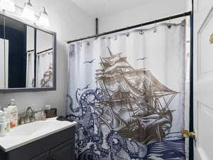 Bathroom with vanity, a shower with shower curtain, and a textured wall