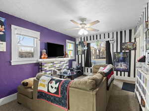 Living room with a textured wall, a textured ceiling, carpet floors, and a ceiling fan
