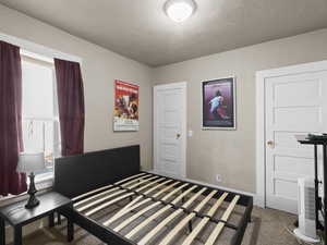 Bedroom featuring dark colored carpet and a textured ceiling