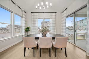 Dining area with light wood-style flooring, hanging lights, and vaulted ceiling