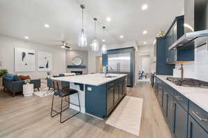 Kitchen with light stone counters, open floor plan, a kitchen breakfast bar, and light wood-style floors