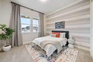 Bedroom with wallpapered walls, light carpet, and an accent wall