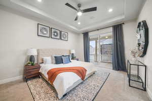 Bedroom featuring a tray ceiling, light carpet, ceiling fan, access to outside, and recessed lighting