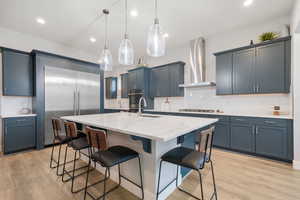 Kitchen featuring decorative backsplash, a kitchen breakfast bar, an island with sink, and light wood-type flooring