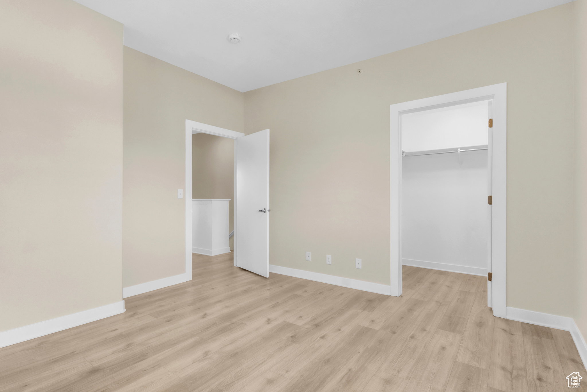 Unfurnished bedroom with a spacious closet and light wood-style flooring