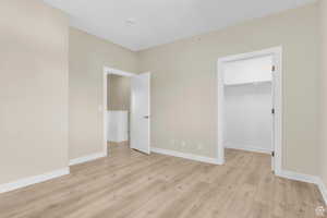 Unfurnished bedroom with a spacious closet and light wood-style flooring
