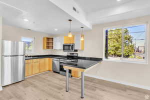 Kitchen with pendant lighting, a peninsula, appliances with stainless steel finishes, modern cabinets, and open shelves