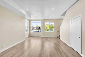 Unfurnished living room with stairs, light wood-type flooring, and recessed lighting