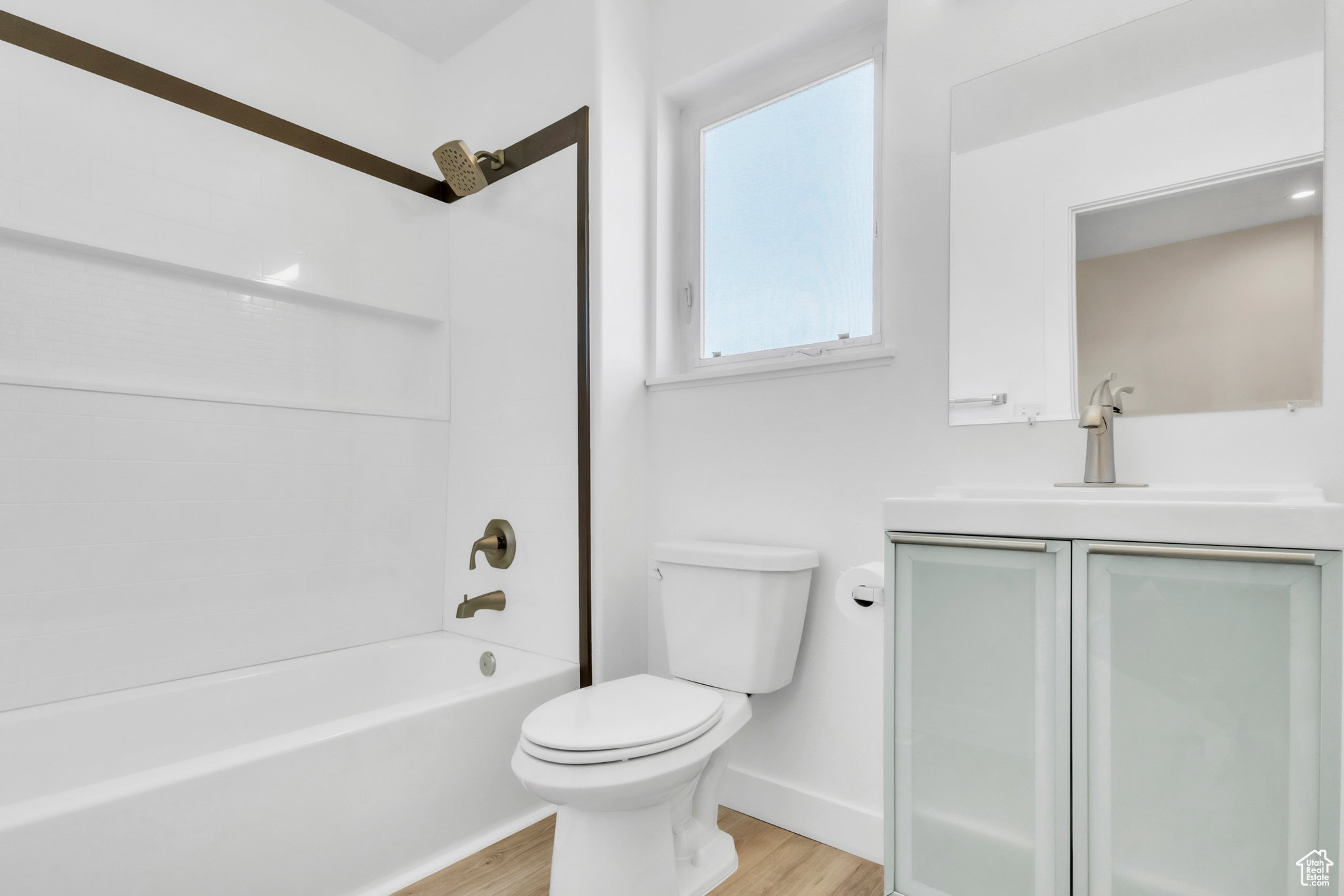 Bathroom featuring shower / bath combination, vanity, and light wood finished floors