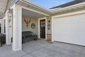 View of exterior entry featuring a shingled roof and a garage