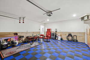 Garage featuring wood walls, a heating unit, freestanding refrigerator, and a garage door opener