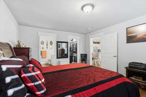 Bedroom featuring a walk in closet, stainless steel fridge with ice dispenser, and ensuite bathroom