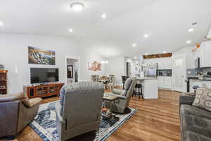 Living room featuring lofted ceiling, recessed lighting, light wood finished floors, and a chandelier