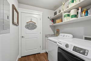 Laundry room featuring electric panel, dark wood-style flooring, washer and clothes dryer, and a textured ceiling