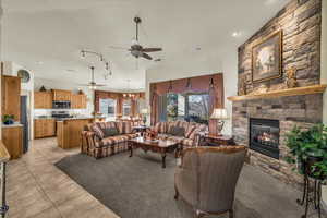 Living area featuring a stone fireplace, ceiling fan, and light tile patterned flooring