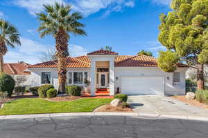 Mediterranean / spanish-style home featuring driveway, a tiled roof, an attached garage, stucco siding, and a front yard