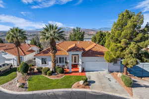 Mediterranean / spanish house with stucco siding, a front yard, concrete driveway, and an attached garage