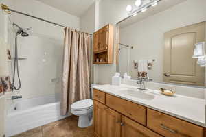 Bathroom featuring shower / bathtub combination with curtain, vanity, and dark tile patterned floors