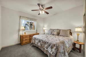 Carpeted bedroom with ceiling fan and baseboards