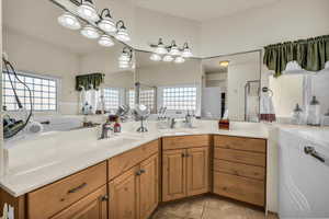 Full bath featuring double vanity, healthy amount of natural light, and a bath