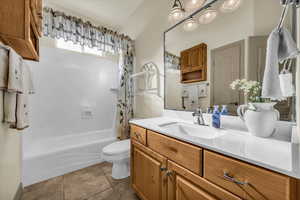Bathroom with vanity, shower / bath combo, and dark tile patterned flooring