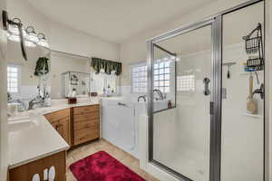Full bath with vanity, a shower stall, plenty of natural light, and light tile patterned floors