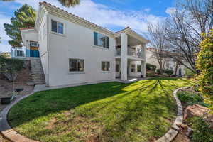 Rear view of house featuring stairway, stucco siding, a yard, a patio, and a balcony