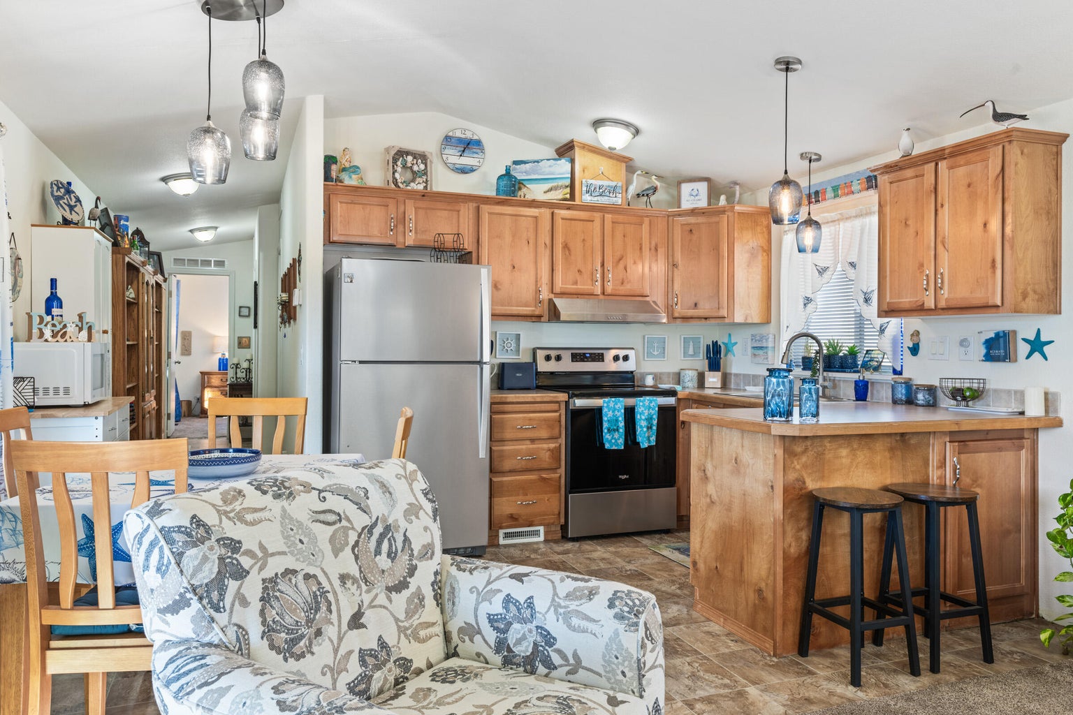 Kitchen featuring pendant lighting, a breakfast bar area, appliances with stainless steel finishes, light countertops, and vaulted ceiling