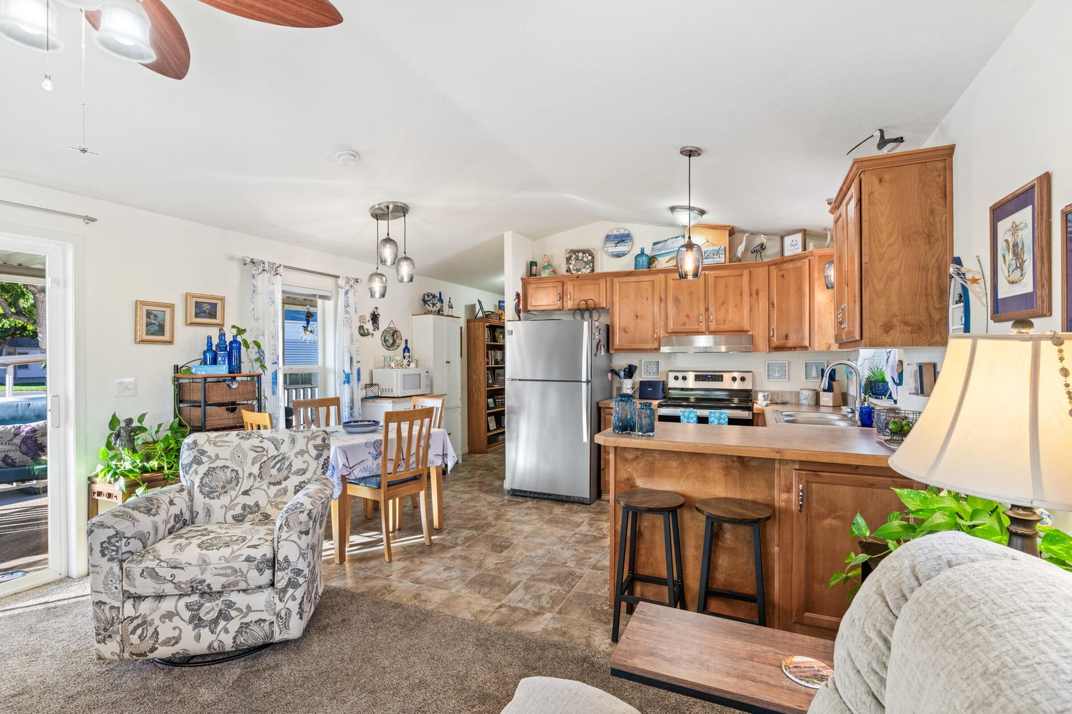 Kitchen with a peninsula, decorative light fixtures, stainless steel appliances, brown cabinets, and lofted ceiling