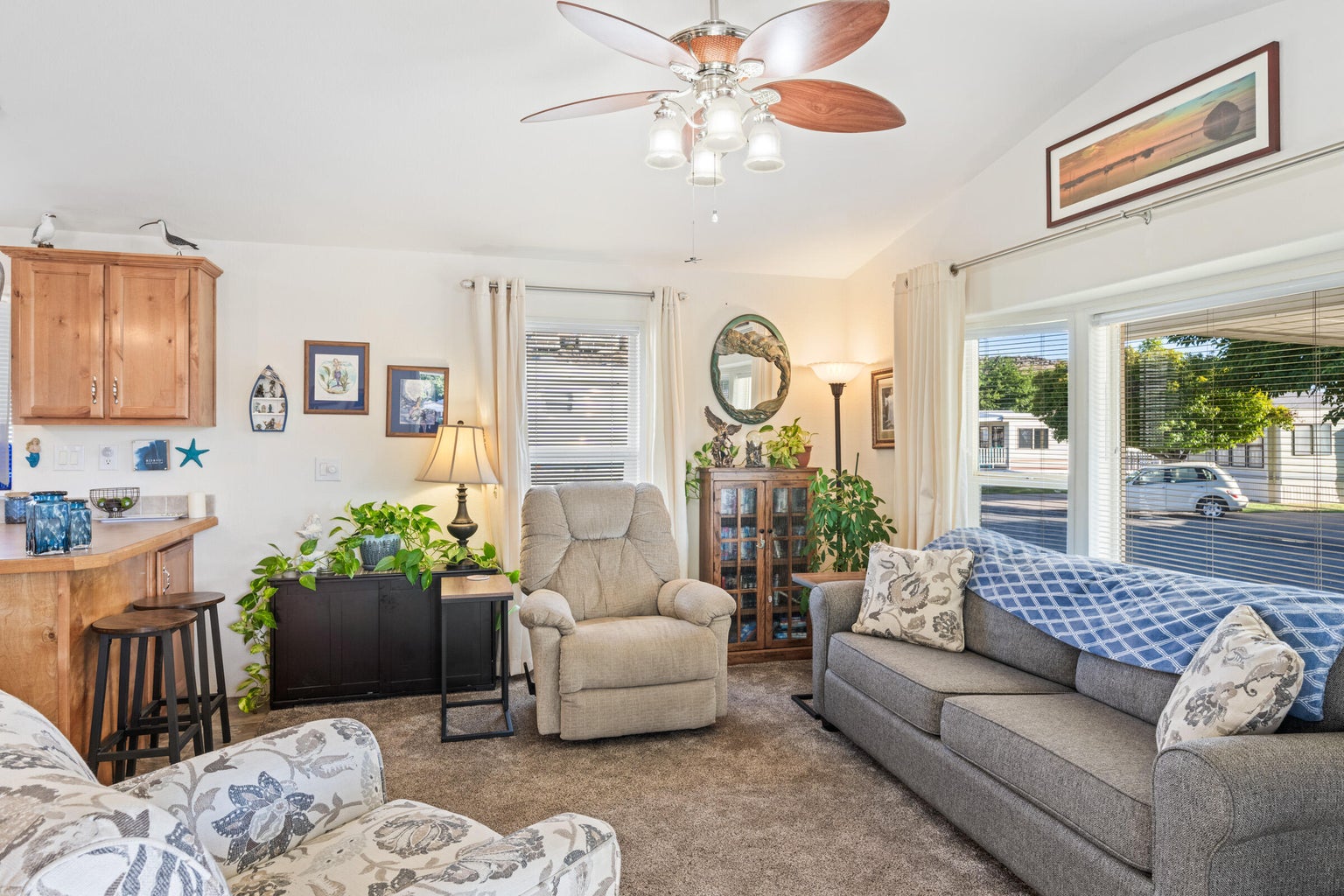 Carpeted living room with vaulted ceiling and ceiling fan