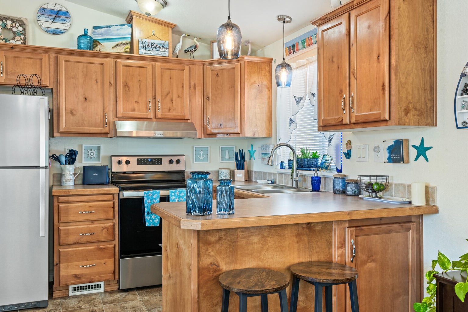 Kitchen with stainless steel appliances, a kitchen bar, pendant lighting, light countertops, and under cabinet range hood